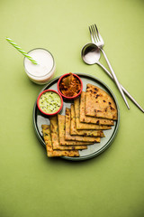 Aloo Paratha / Indian Potato stuffed Flatbread with butter on top. Served with fresh sweet Lassi, chutney and pickle . selective focus