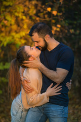 Young couple in love hugging and kissing in the Park. They are illuminated by a ray of sunlight. In the background autumn forest.