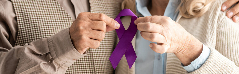 panoramic shot of senior man and woman holding purple ribbon