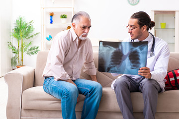 Obraz premium Young male doctor visiting old patient at home