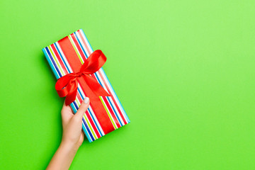 Top view of female hands holding christmas or other holiday handmade present box package in the palms, flat lay table background with copy space