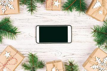 White black smartphone with isolated screen, above wooden desk with Christmas decorations. Top view. Toned
