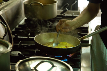 Hand man cooking with a steel pot on the stove in the kitchen