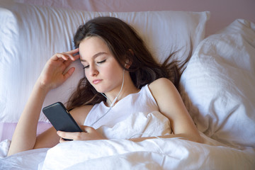 Teen girl using cell phone on waking feels good in the morning on the bed