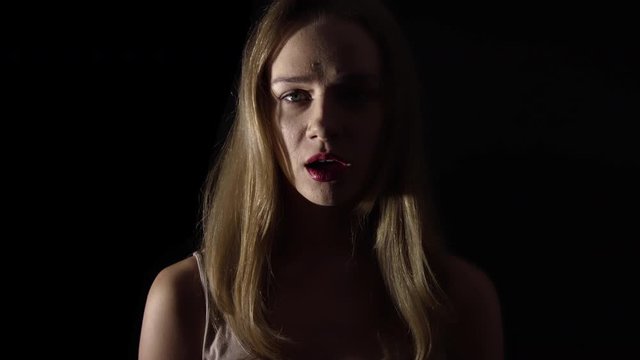 Terrified woman on black background. Scared facial expression in horror, slowmotion.