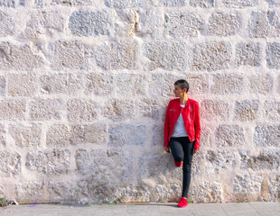 young woman short black hair red jacket stone wall