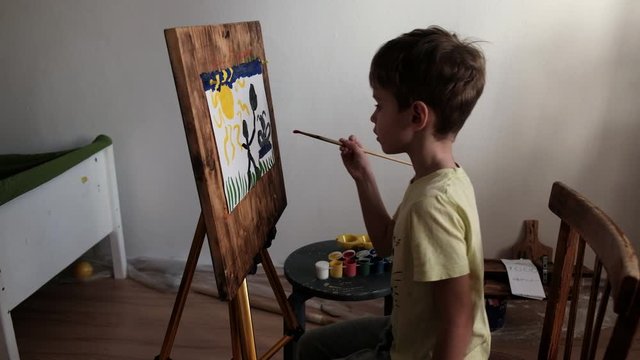 preschool boy paints on a easel with gouache paint with a brush. 4k