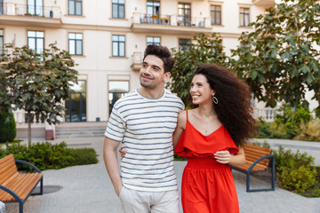 Image of happy couple clothes smiling and hugging while walking