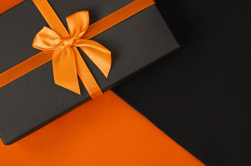 A stylish gift box on duotone orange and black background with copy space