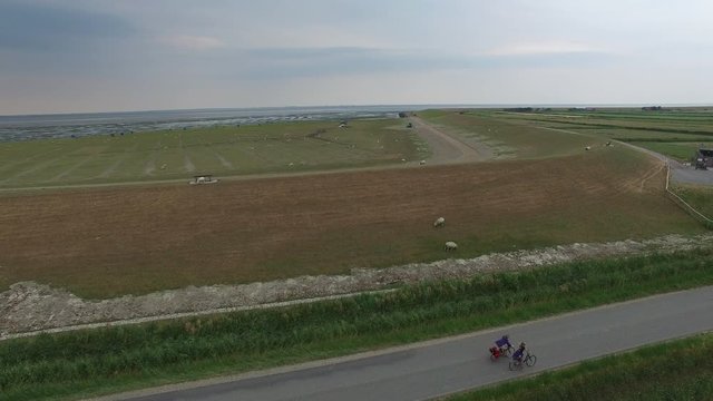 drone aerial at coast of Pellworm in Germany, with cyclists and windmill