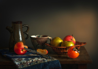 Still life with fruits. Apples and Persimmons. One apple is cut. Nearby lies a cut wedge. Kitchen. Vintage.