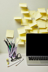 laptop with blank screen near empty sticky notes and pen holder with stationery on grey and white