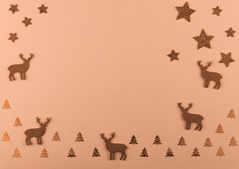 New Year and Christmas composition. Christmas deer and fir-trees, golden decorations on bright peach background.  Flat lay with copy space. Top view