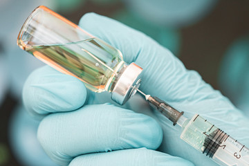 blue gloved medical worker draws an ampoule vaccine into a syringe. Medical flu shot concept. injection bottle for medical glass vials