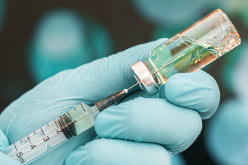 blue gloved medical worker draws an ampoule vaccine into a syringe. Medical flu shot concept. injection bottle for medical glass vials