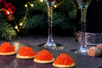 New Year and Merry Christmas concept. 2 glasses of champagne, tartlets with red caviar, spruce...