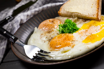 Fried eggs and bread for breakfast on a gray background.