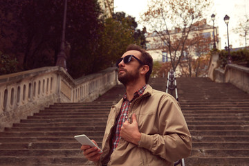 Handsome man using cellphone in European city.