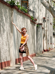 Portrait of happy Chinese girl in yellow halter top and short skirt posing on sunny street with...