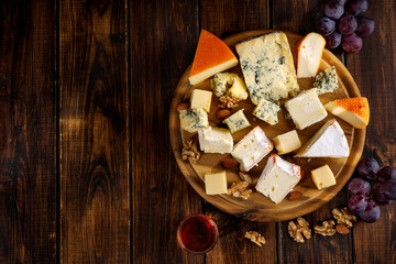 Top view of many cheese sorts served on wooden board