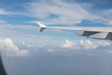 Fototapeta na wymiar Wing of airliner, in the background beautiful blue sky and clouds. Travel and vacation concept.