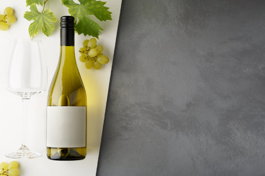 Bottle of white wine with label. Glass of wine and grape. Wine bottle mockup.
