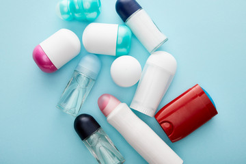 top view of roll on and spray bottles of deodorant on blue background - obrazy, fototapety, plakaty