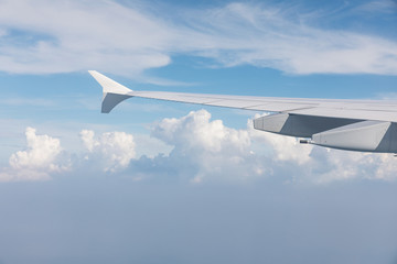 Wing of airliner, in the background beautiful blue sky and clouds. Travel and vacation concept.