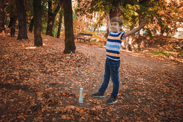 Little boy doing bottle flip in the park.