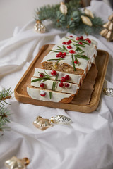 selective focus of traditional Christmas cake with cranberry on wooden board near baubles and pine on white cloth isolated on grey