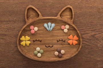 top view of feline dry pet food and vitamins in cute cat shape plate on wooden table