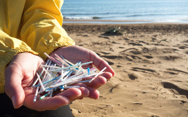 Hands full of  plastic ear sticks collected on the beach. Ocean plastic pollution concept.