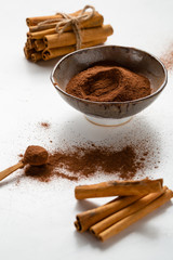 Cinnamon powder in bowl and sticks