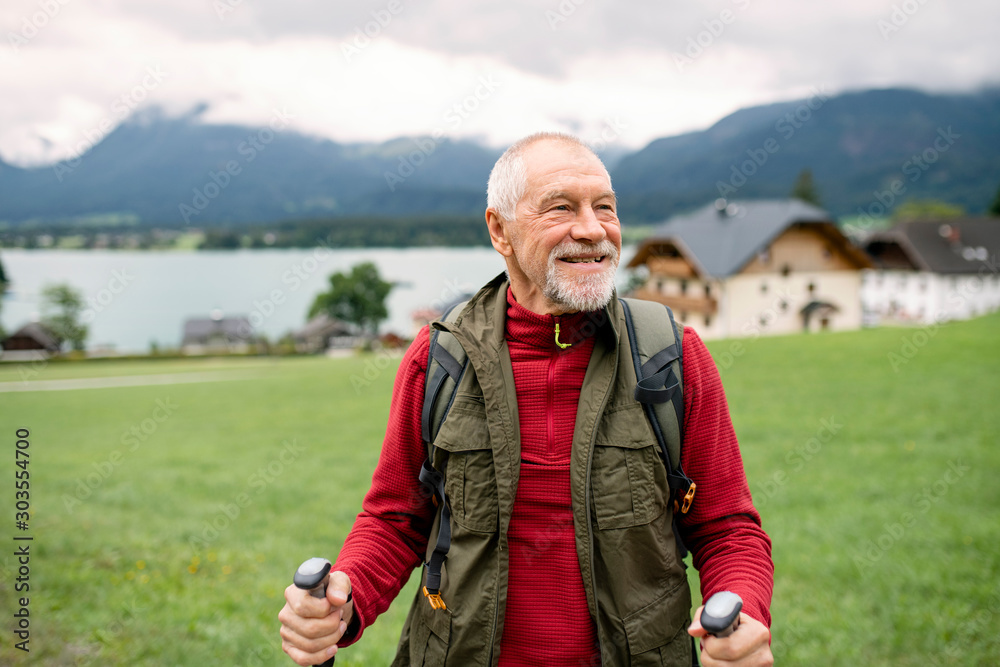 Sticker senior man with nordic walking poles hiking in nature, resting.