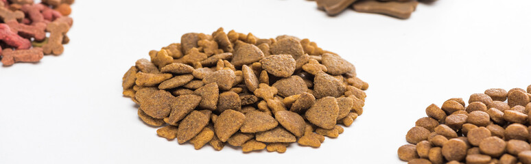 selective focus of fresh assorted dry pet food in piles isolated on white, panoramic shot