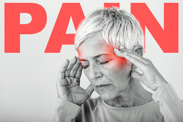 Woman suffering from stress or a headache grimacing in pain. Senior woman with migraine feeling...