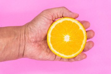 Organic freshness Orange cutting on male hand Isolated pink background