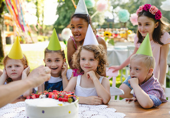 Down syndrome child with friends on birthday party outdoors in garden.