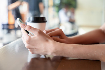 woman hand holding smartphone, working or using internet connection in coffee shop or cafe. Concept of modern working women freelancer, high technology lifestyle