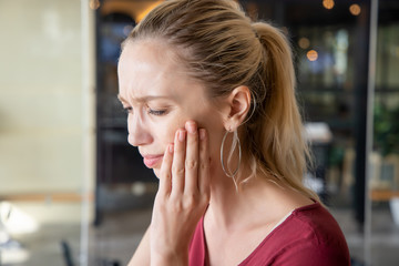 woman with toothache; sick caucasian woman suffering from toothache, tooth decay, tooth sensitivity, cavity, dental care concept; young adult white woman model with blonde hair