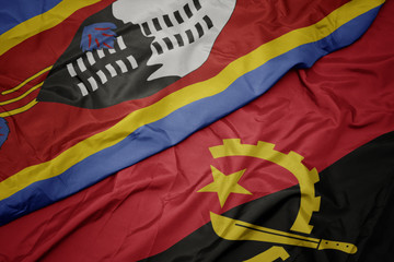 waving colorful flag of angola and national flag of swaziland.
