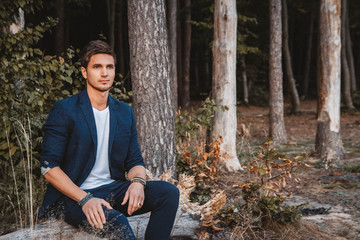 Handsome man posing outdoors in forest wearing checked jacket. Place for text or advertising