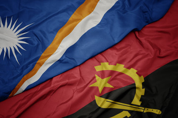 waving colorful flag of angola and national flag of Marshall Islands .