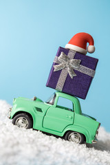 Side view of small car with Christmas holiday equipment driving through snow abstract.