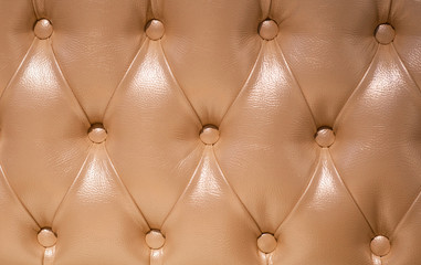 Coach-type  screed tightened with buttons. Chesterfield style quilted upholstery backdrop close up