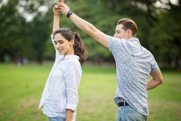 Obraz premium Outdoor shot of young couple in love joyful in the park through grass field. Man and woman hugging and Laugh on grass field.