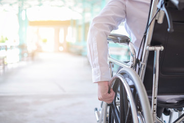 Cropped image of man holding wheelchair outdoors - obrazy, fototapety, plakaty
