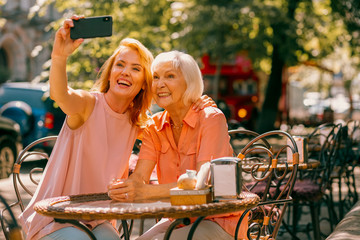 Happy adult woman taking selfie with mother stock photo