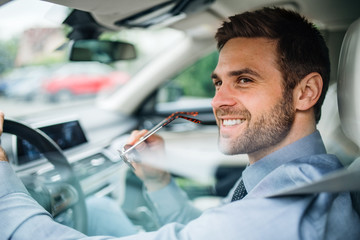 Young businessman with shirt sitting in car. Shot through glass.