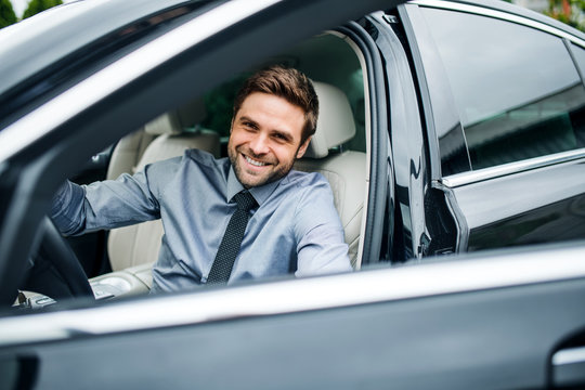 Young Man With Blue Shirt And Tie Getting Out Of Car In Town.